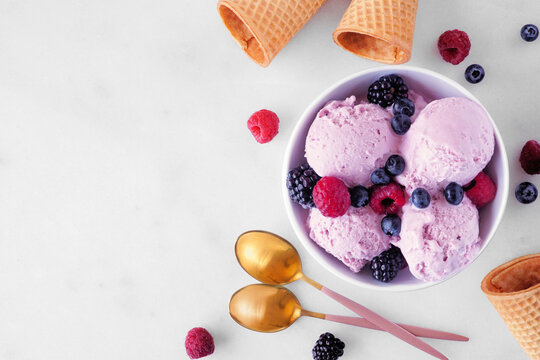 Bowl of field berry ice cream. Top view table scene with copy space over a white marble background.