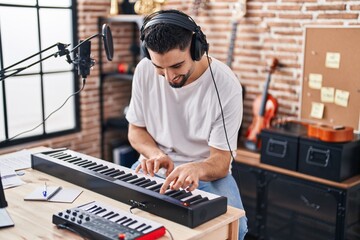 Young arab man musician playing piano keyboard at music studio