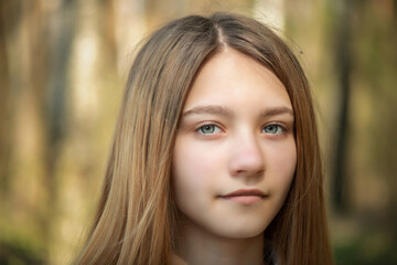 Portrait of a young beautiful blonde girl in a summer park.