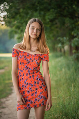 Fototapeta premium Portrait of a young beautiful blonde girl in a summer park.