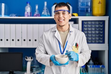 Young arab man working at scientist laboratory winking looking at the camera with sexy expression,...