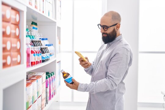 Young bald man customer make photo by smartphone to medicine bottle at pharmacy