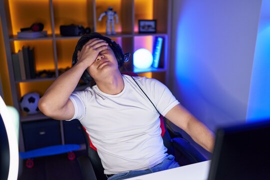 Young chinese man streamer stressed using computer at gaming room