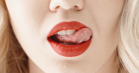 Close up shot of sensual blonde girl seductively licking and biting lips with bright red lipstick ....