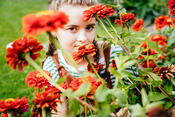 Sad teenager girl arround the flowers in the garden.