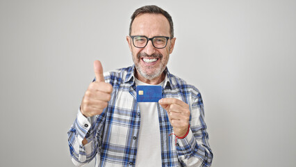 Middle age man pointing to credit card doing thumb gesture over isolated white background