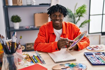 African american man artist smiling confident drawing on notebook at art studio