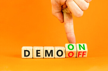 Demo on or off symbol. Businessman turns wooden cubes and changes word Demo off to Demo on. Beautiful orange table orange background. Business and demo on or off concept. Copy space.