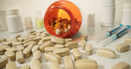 Close up shot of pills from a medicine can near different types of pharmacy and drugs, on white...
