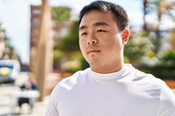 Young chinese man standing with relaxed expression at street