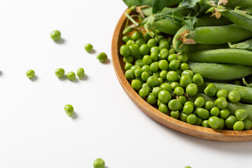 Green peas pods and seeds on wooden plate