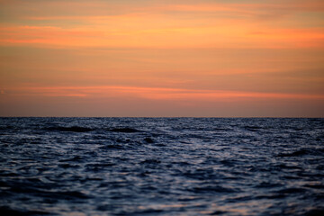 Dramatic red ocean waves at sunset with soft evening sea dark water