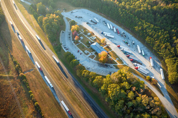 View from above of big parking rest area for cars and trucks near busy american highway with fast moving traffic. Recreational place during interstate travel