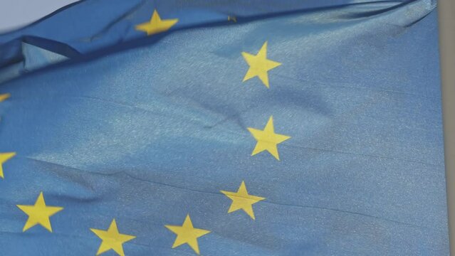 The sun breaks through the silk fabric of the flag of the European Union