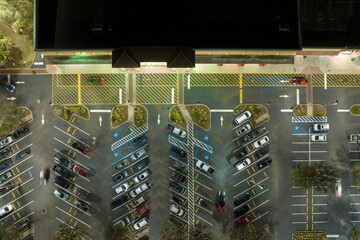 View from above of many parked cars on illuminaded parking lot with lines and markings for parking places and directions. Place for vehicles in front of a shopping mall center © bilanol