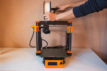 Technological hi-teg tool for making new things. A black and red 3D printer at work. The object is created by laying down continuous layers of material in additive processes.