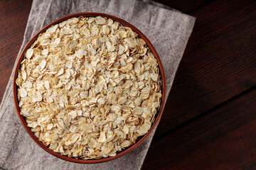 Oat flakes bowl on a linen napkin. Dry rolled oatmeal on wooden boards. Vegan food concept. Copy space