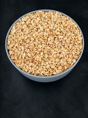 Oat flakes in a bowl on a dark background. Uncooked rolled oats for a healthy diet. Gluten free diet concept. Copy space