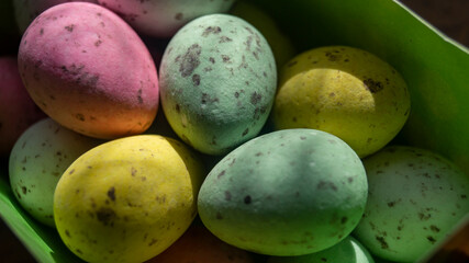 Small multicolored eggs. Small chocolate eggs in a box. Small eggs of different colors close-up