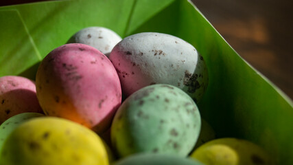 Small multicolored eggs. Small chocolate eggs in a box. Small eggs of different colors close-up