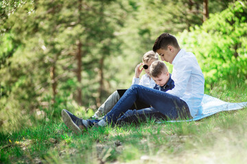 children sit in the park and play on the laptop