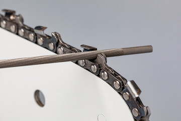 Sharpening chainsaw chain with file. Chain saw and lawn equipment maintenance, repair and service concept.