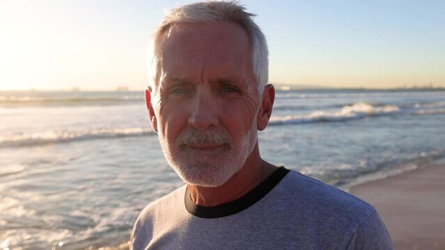 Portrait of a 64 year old man at the beach at sunset. Slow Motion.