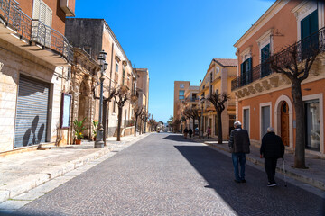 a sunny downhill street of a typical Sicilian town