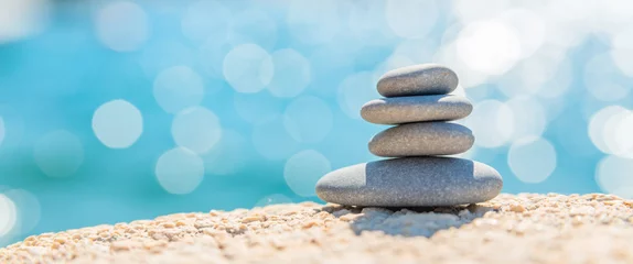 Tuinposter Stenen in het zand Pyramid stones on the seashore on a sunny day on the blue sea background. Happy holidays. Pebble beach, calm sea, travel destination. Concept of happy vacation on the sea, meditation, spa, calmness.