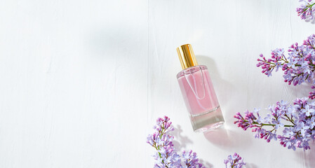 Obraz na płótnie Canvas Pink glass perfume bottle and lilac branches on a white background