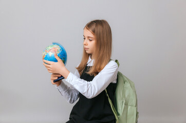 Fototapeta premium Caucasian young teenager schoolgirl student holding a globe on a gray background, isolated. Happy earth day