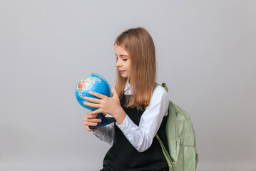 Caucasian young teenager schoolgirl student holding a globe on a gray background, isolated. Happy earth day