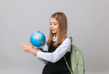 Caucasian young teenager schoolgirl student holding a globe on a gray background, isolated. Happy earth day