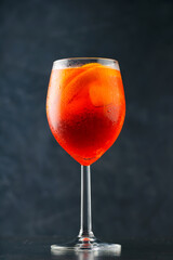 Aperol Spritz cocktail on dark background. Cocktail Aperol Spritz with oranges and ice cubes in glass. Summer refreshing drink