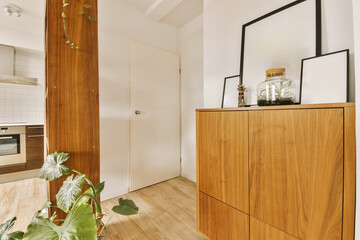 a kitchen and dining area in a house with wood flooring, white walls and wooden cabinetd cupboards