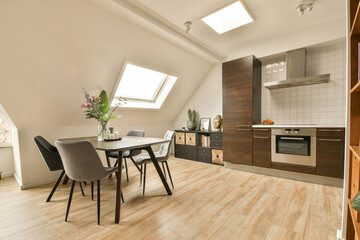 a kitchen and dining area in a room with wood floors, white walls, and skylights above the windows