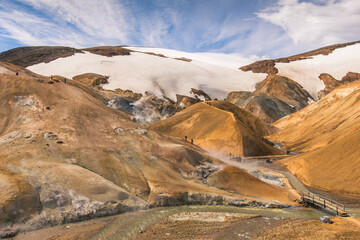 Snow-capped mountain tops in Hveradalir (valley of the hot springs) geothermal area with bridge and...