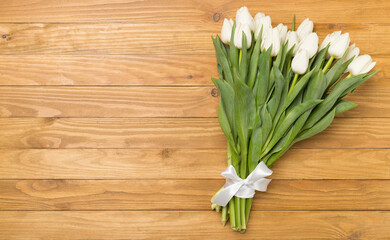 White tulip bouquet on wooden background, top view