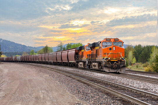 freight train with a colorful sunset in background near Whitefish, Montana