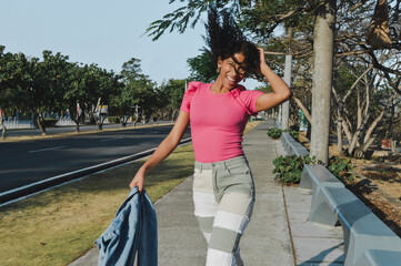 girl with afro hair enjoying while dancing in the street, having fun, smiling, carefree girl enjoys life, lifestyle concept