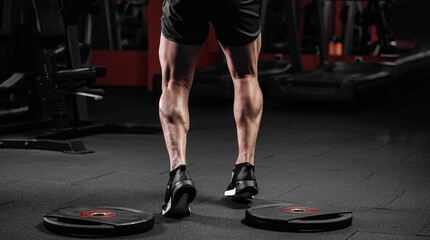 Trained man's legs with muscular calves in sneakers in fitness training gym © VlaDee