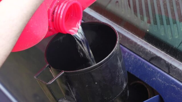 Pouring fuel with funnel in a car gas tank from red can