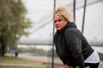 Obese middle aged woman resting after an outdoors workout.