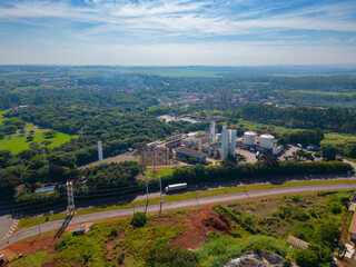 Naklejka premium Aerial image of chemical industry. Large structure of pipelines and warehouses with movement of cargo trucks. Industry surrounded by vast vegetation and trees. Located in Brazil, city of Paulínia.