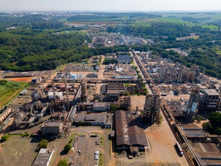 Aerial image of chemical industry. Large structure of pipelines and warehouses with movement of cargo trucks. Industry surrounded by vast vegetation and trees. Located in Brazil, city of Paul&iacute;nia.