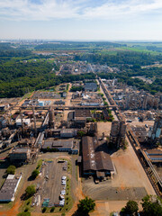 Aerial image of chemical industry. Large structure of pipelines and warehouses with movement of cargo trucks. Industry surrounded by vast vegetation and trees. Located in Brazil, city of Paulínia.