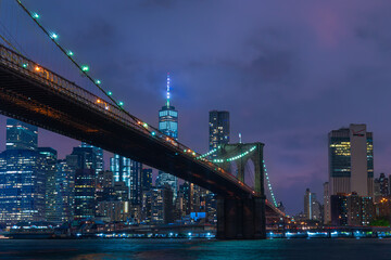 Skyline of downtown New York City Brooklyn Bridge and skyscrapers over East River illuminated with lights at dusk after sunset view from Brooklyn	