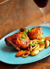 Pollo horneado con vegetales y una copa de vino tinto.