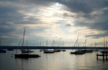 Fototapeta na wymiar a tranquil scenery with sailing boats resting on calm lake Ammersee in Herrsching on an overcast serene evening in spring (Herrsching on Ammersee, Bavaria, Germany)
