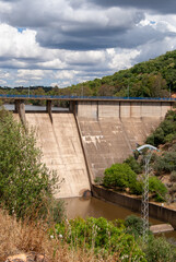 Obraz premium Imagen vertical de la presa de un embalse bajo un cielo nublado.